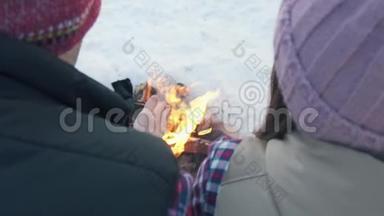 一对戴着结婚戒指的年轻人穿着冬装在树林里，在火堆旁暖手，过<strong>寒假</strong>