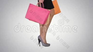 带有渐变背景购物袋的购物女士的步行腿。