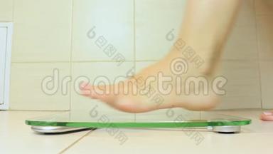 女人光着脚站在秤上，在浴室里称重-饮食和减肥概念