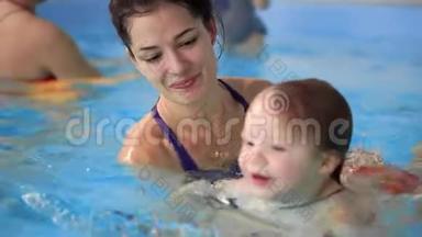快乐的中年妈妈和可爱的可爱宝宝在游泳池游泳.. 微笑的妈妈和小孩，新生的女孩