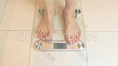 女人光着脚站在秤上，在浴室里称重-饮食和减肥概念