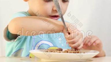 一个孩子正吃着荞麦粥里夹着肉，坐在一张桌子上，背景白色，特写..