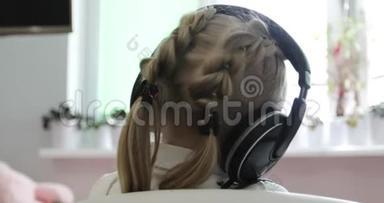 一个扎着马尾辫，扎着辫子的小女孩正在耳机上听音乐..