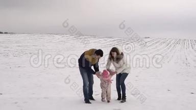 爸爸妈妈被教导在雪地里走我的女儿。 冬季家庭步行