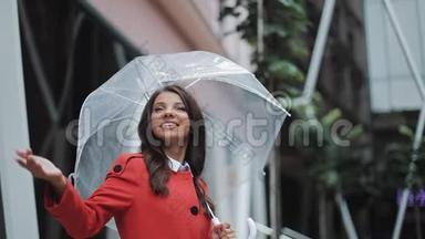 帅气的年轻女商人仰望天空，举起手来检查雨是否停了。她微笑着靠近