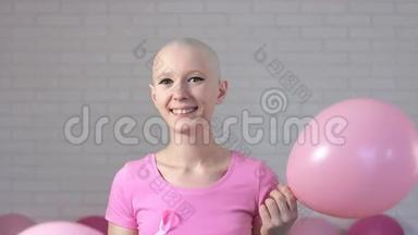 幸福的乳腺癌幸存者女人从粉红色的气球里出来，微笑着看着镜头-乳腺癌