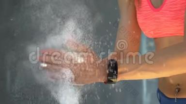肌肉发达的女人在健身房用<strong>滑石</strong>粉拍手。