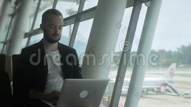 成功的商人在机场等待航班时使用笔记本电脑。