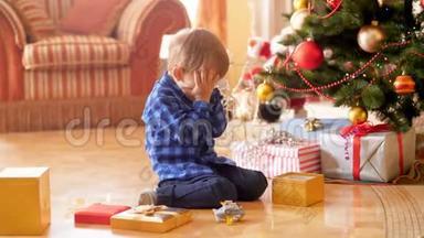 4K录像显示，小男孩因圣诞老人送的礼物而<strong>坐在</strong>圣诞<strong>树下</strong>哭泣