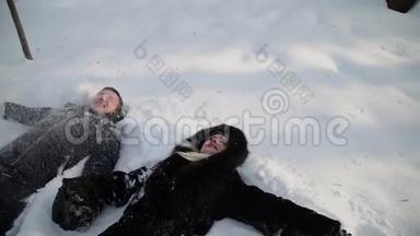 美丽的年轻夫妇牵着手在雪地上玩得很开心。 城市冬季公园。