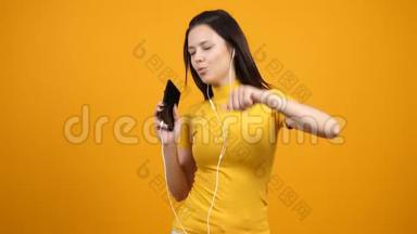 快乐的女人在智能手机上一边听音乐一边跳舞和唱歌