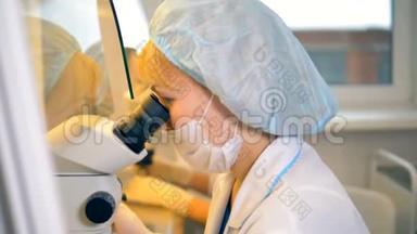 两位女科学家正在实验室做实验，其中一位正在显微镜下观察