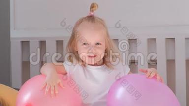 小可爱的金发女孩<strong>坐</strong>在她房间里的床上，带着粉红色的<strong>气球</strong>，微笑着。 肖像。