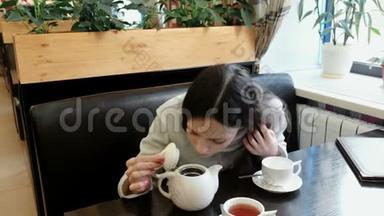 黑发女人打开茶壶，闻了闻，把茶壶里的茶倒进杯子里。
