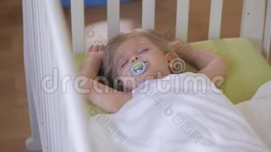 一个小女孩睡在婴儿床上，嘴里放着奶嘴