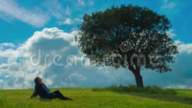 孤独的女人坐在绿树<strong>下</strong>，享受着晴朗的风和日丽的天气，想着