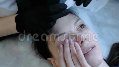 美容治疗。 美容师在女人的眼睛下面贴补丁。 上景。