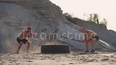 两名男运动员一起训练，在山上的沙滩上用锤子<strong>敲打</strong>着方向盘。 耐力