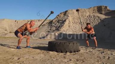 两名男运动员一起训练，在山上的<strong>沙</strong>滩上用<strong>锤</strong>子敲打着方向盘。 耐力