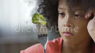 可爱的非裔美国人孩子看着叉子和西兰花片，有机食品