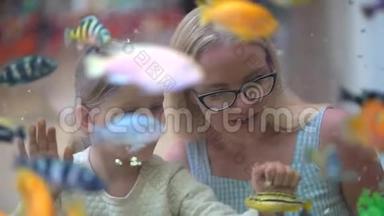 孩子，看着小女孩，在购物中心的水族馆里看鱼。 宠物店。 妈妈和她的小女儿看海