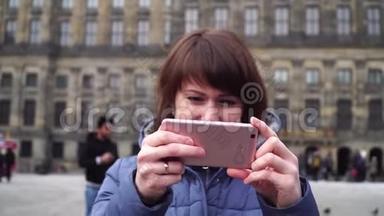 女孩在大坝广场的智能手机上拍照。 阿姆斯特丹