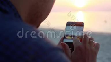 在美丽的夕阳下，帅哥在海滩上的酒吧休息时使用手机。 有人在网上发布照片