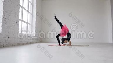 可爱的体操运动员在画室里用白色背景的腿做圆圈。 体操学校。 体操女孩