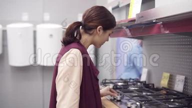 年轻的黑发女孩在厨房的<strong>灶台上</strong>按下燃烧机按钮，并从硬件显示价格标签