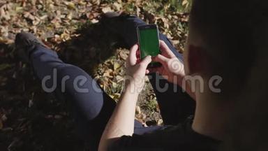 男子手持黑色智能手机，绿色<strong>屏</strong>幕上的城市街道背景在晴天。 <strong>大屏</strong>幕。 科布尔街