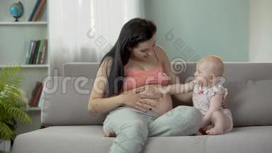 可爱的宝贝女孩在大肚子上拍着<strong>孕妈妈</strong>，快乐的分娩
