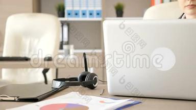 女商人在她的办公桌上打字，然后插入笔记本电脑的音频和麦克<strong>风电</strong>线