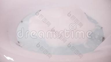 一个现代圆形浴缸，配有按摩浴缸，里面充满了泡沫肥皂泡沫的鼓泡水，里面没有人。 4k，慢动作