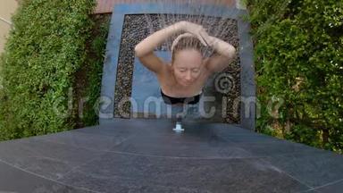一个年轻女人在热带花园里洗澡的慢镜头。 在热带度假胜地度假的概念。 年轻女子