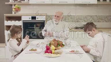 在一家人吃饭前，爷爷和孙子们在餐桌上交流