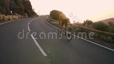<strong>一</strong>个戴着头盔和运动装备的专业骑自行车的人<strong>在</strong>日落时缓慢地骑<strong>在</strong>山区公<strong>路上</strong>。 Stadicam