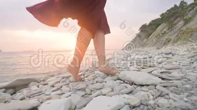 在日落时分，一个穿着红色裙子在风中飘舞的赤脚女孩的腿后，特写慢动作