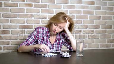 生病的悲伤的女人坐在桌边整理药片。 保健和维生素缺乏的概念。