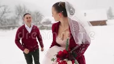 年轻的新婚夫妇跑着，在滑雪胜地的村庄里玩着玩，手里拿着木头小屋，靠近原木。 冬季