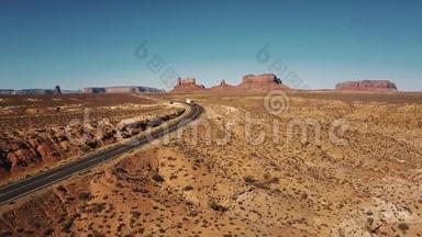 在美国纪念碑山谷，红色<strong>货运卡车</strong>沿着沙漠公路行驶，具有惊人的山脉天际线。