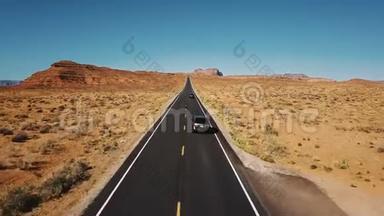 无人机跟随两辆汽车沿着美丽的公路公路行驶，纪念碑谷，宽阔开阔，一望无际的干燥沙漠景观。