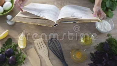 女人的手拿着烹饪书，女孩选择食谱和翻页