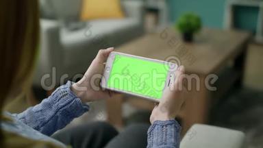 女人在家用绿色锁屏智能手机在沙发上唱歌