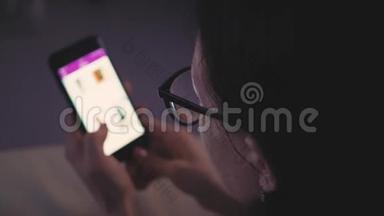 一位戴眼镜的女士坐在沙发上，用智能手机进行网上购物。 网上营销