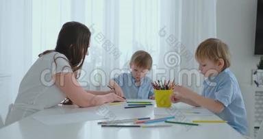 夏天，妈妈和她的两个儿子坐在厨房的桌子上画彩色<strong>铅笔</strong>，一家人在草坪上<strong>画画</strong>。