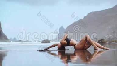 女人在靠近大海的沙滩上，在群山和黑沙上翩翩起舞