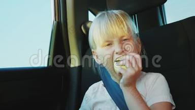 一个6岁的女孩在车里吃苹果。 在路上容易饥饿和零食