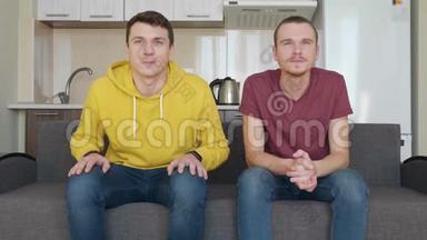 两个人坐在沙发上看电视上的足球比赛，享受他们最喜欢的球队的胜利