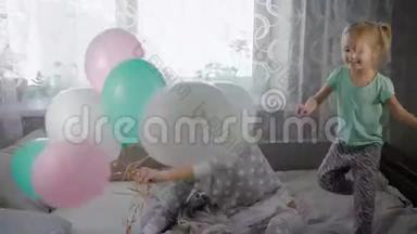 幸福的一家人在家里的床上玩睡衣派对。 姐姐正抱着五颜六色的空气