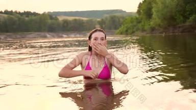 穿着泳衣的女孩潜入水中，在夏天的晚上大笑。 海滩季节。 慢动作